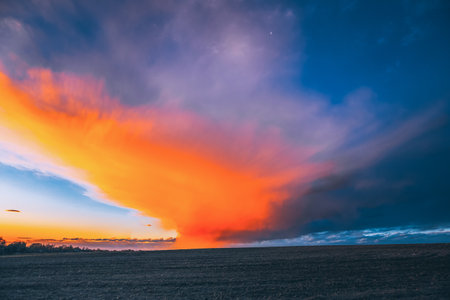 Spring Field At Sunset Sunrise. Morning Sunrise Evening Sunset Sky Above Dark Countryside Meadow Landscape. Spring Natureの写真素材