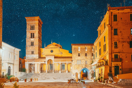 Terracina, Italy. Bold Bright Blue Night Starry Sky With Glowing Stars Above Tower Of Cathedral Of San Cesareo In Night Time. It Built On Podium Of Temple Of Roma And Augustus. Travel To Italyの写真素材