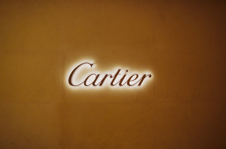 Dubai, UAE, United Arab Emirates - May 28, 2021: Golden logotype Cartier jeweler Brand at wall of store in shopping center. Cartier International SNC, or Cartier is French luxury goods conglomerate which designs, manufactures, distributes, sells jewelleryのeditorial素材