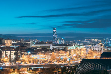 Tbilisi, Georgia - March 25, 2022: Radisson Blu Hotel On Background Of Urban Cityscape during sunset evening lights. Elevated view Tbilisi skyline during evening,のeditorial素材