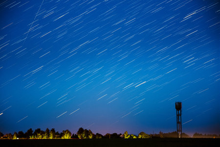 Amazing Unusual Stars Effects In Sky. Stars Lines Move Above Rural Landscape Water Tower In...