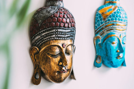 Close up of handmade souvenirs buddha mask on white background under branches. Details