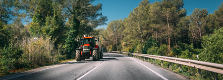 Tractor With Fertilizer Applicator With Tank In Motion On Country Road In Europe.の写真素材