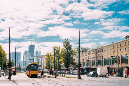 Warsaw, Poland. People Cross The Tram Tracks On The Jana Pawla Ii Street. Yellow Public Old Retro Tram On Modern Skyscraper Backgroundのeditorial素材