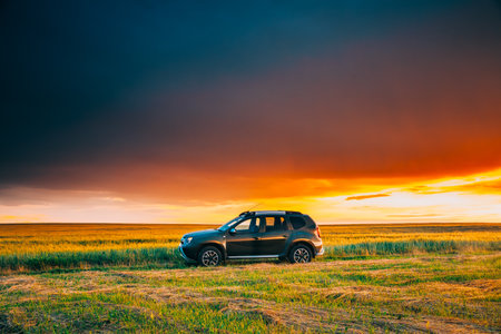 AWD 4WD SUV green car in summer meadow landscape in summer field countryside landscape. Sunset sky backgroundの写真素材