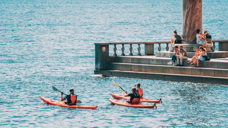 Stockholm, Sweden. People Floating On Kayak Near Scenic Famous View Of Embankment In Old Town Of Stockholm At Summer. Gamla Stan In Summer Evening. Popular Destination Scenic Place.のeditorial素材