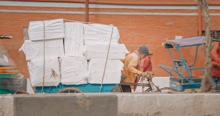 New Delhi, Delhi, India. Indian man carries loaded cargo on a cargo bike. Traffic On The Desh Bandhu Gupta road street. Cargo Lorry Trishaw pedicab moving on a bicycle along the street. Cars, Motorcycles, Auto Rickshaw Or Tuk-tuk Moving On Street In morniのeditorial素材