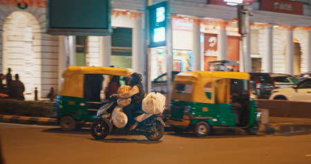 New Delhi, Delhi, India. Indian man carries loaded cargo on a bike. Traffic On The Connaught Lane street in night time.のeditorial素材