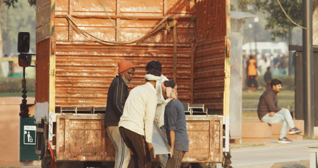 New Delhi, Delhi, India. Indian men loading heavy iron structures into the back of a truckのeditorial素材