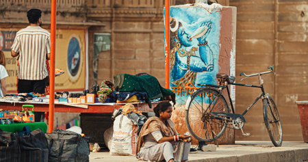 Varanasi, India. Indian Woman Eating Street Food At Ghat Near Gangaa River. Woman Eat At Riverbank Embankment In Summer Sunny Day. Every Day Life Of Indiaのeditorial素材