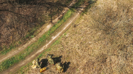 Men dressed as soldiers of infantry of World War II sneaking around in spring autumn day. Soldiers prepare mortar for battle in dry grass. Aerial view elevated shotの写真素材