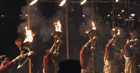 Varanasi, India. Man makes movements with a candle holder with lit candles on the Ganga Maha Aarti ceremony begins. Brahman priest wearing red and yellow dress doing traditional ganga aarti at ghat, Varanasi, Uttar Pradesh, India Puja ritual in Varanasi. のeditorial素材