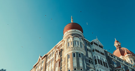 Mumbai, India. Blue Clear Sky In Sunny Day With Fly Pigeon Birds In Above Taj Mahal Palace. Finest Hotel In East. Close-up View On Taj Mahal Hotel Is Heritage, Five-star, Luxury Hotel In Colaba Area Of Mumbai Situated Next To Gateway Of Indiaのeditorial素材