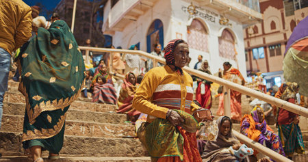 Varanasi, Uttar Pradesh, India. Indian woman going to night Ganga Maha Aarti ceremony on Dashashwamedh Ghat. night time illumination lights. People visiting Puja ritual near Hindu temples.Hundreds of tourists and locals gather on the steps of the ghat or のeditorial素材