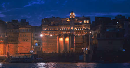 Varanasi, Uttar Pradesh, India. Boat floating near Darbhanga Ghat and old BrijRama Palace. Cityscape of Varanasi. Cinematic Camera movement moving along riverbank embankment. View from riverside in night lights. old wallsの写真素材