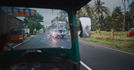 Tuk-tuks and bus on a scenic road under clouded sky