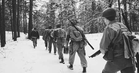 Re-enactors dressed as American infantry soldiers marching through forest road in cold winter day....