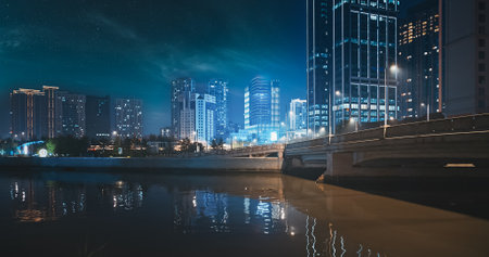 Serene Riverside Night View with Illuminated City Skyline and Reflectionsの写真素材
