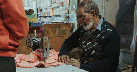 Indian tailor working with red fabric at night marketのeditorial素材