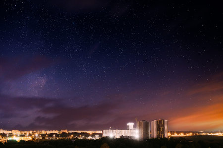 City lights against dramatic night sky with purple and orange hues, meteorological phenomenon with...