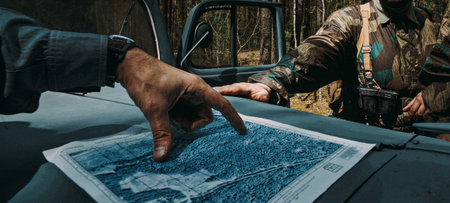 German Army officers looking at a topographic map to plan a route. Hands pointing at a location on...