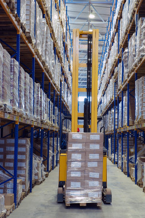 St. Petersburg, Russia - November 21, 2008: Forklift pallet truck traveling along the narrow aisle goods warehouse, with load palletising. A fork lift truck moves stacked pallets.のeditorial素材
