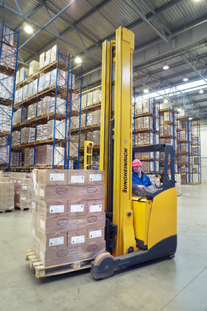 St. Petersburg, Russia - November 21, 2008: The driver of a yellow forklift truck operates, in warehouses, sitting in the workplace. A fork lift truck moves stacked pallets. Forklift palletiser carrying palletising on the territory of the warehouse with pのeditorial素材