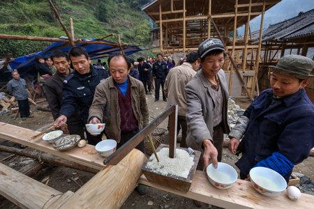 Langde Village, Guizhou, China - April 16, 2010: Peasants, farmers, villagers mountain village celebrate Start of construction of the farmhouse, men drink alcohol, eat rice, fish and eggs.のeditorial素材