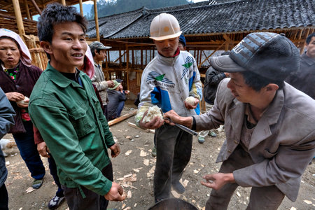 Langde Village, Guizhou, China - April 16, 2010: Peasant gives rice to neighbors at the village holiday, the farmer takes a treat hands.のeditorial素材