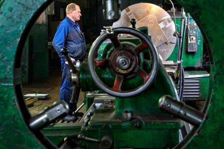 St. Petersburg, Russia - May 21, 2015: Processing of steel parts on a large lathe, turner machine operator controls the process, machine tool workshop in the factory of steel structures.のeditorial素材