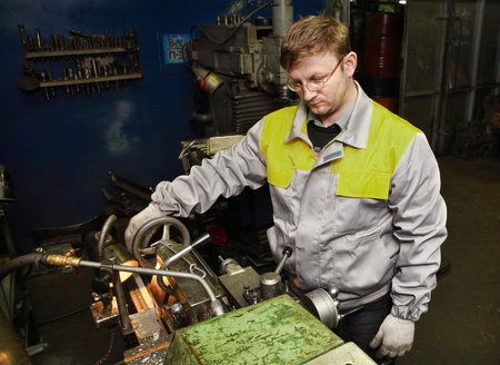 St. Petersburg, Russia - 22 December 2011: Turner machine tool operator handles the steel part on a...