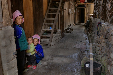 Xijiang miao village, Guizhou Province, China - april 17, 2010: Rural Wooden Peasant Farmer House Yard, Two mature Asian woman and a child, a little boy, about 2 years old.のeditorial素材