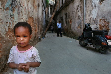 Zanzibar, Tanzania - February 16, 2008: Unknown African child about 6 years old, stands in the courtyard of the house, with old dilapidated walls.のeditorial素材