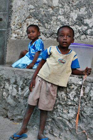 Zanzibar, Tanzania - February 20, 2008: Children from the fishing village, a boy about 8 years old, and a girl about 4 years old, resting in the shade of the stone house.のeditorial素材