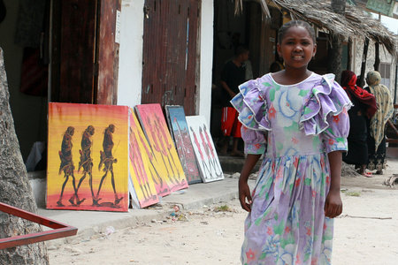 Zanzibar, Tanzania - February 18, 2008: Souvenir shop outdoors, local arts, African girl 10 years old standing near the image of the Maasai.のeditorial素材