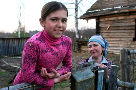 Lipovec village, Tver region, Russia - May 1, 2006: Peasant girl Tanya 11 years old, standing at the fence near the farmhouse, not far from his mother spring evening.のeditorial素材