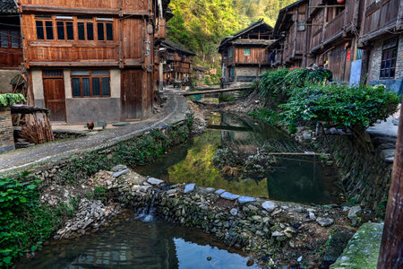 Zhaoxing Dong Village, Guizhou Province, China -  April 8, 2010: Dam on a rural river flowing between the wooden houses countryside of ethnic minorities in mountainous areas.のeditorial素材