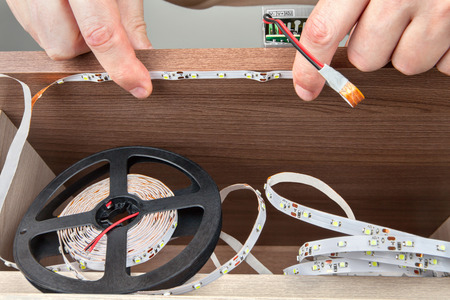 Close-up of a hand electrician, installation LED strip inside the cabinet.の写真素材
