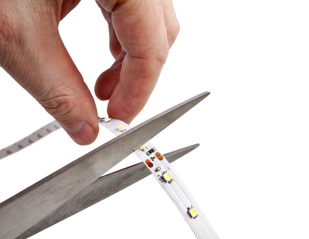 Close-up of hands hold scissors that are cutting LED strip, isolated on white background.の写真素材