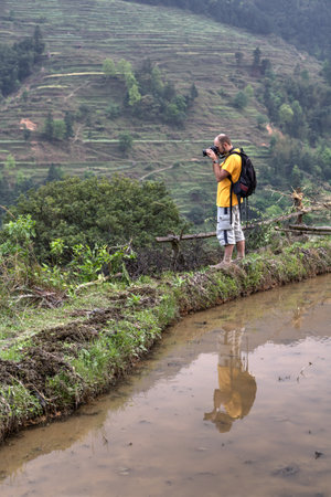 Zhaoxing Dong Village, Guizhou Province, China -  April 9, 2010: European traveler photographs farmland spring in Chinaのeditorial素材