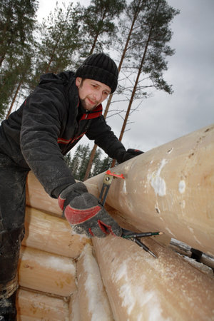 Leningrad Region, Russia - February 2, 2010: Scribing the log, Worker makes logs markup.のeditorial素材