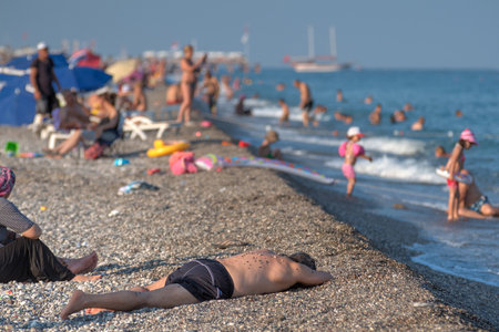Antalya, Turkey - 25 august, 2014: The beach on the shore of the Mediterranean Sea, the man is dozing, lying on the gravel.のeditorial素材