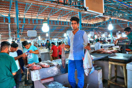 Bandar Abbas, Hormozgan Province, Iran - 16 april, 2017: The young seller demonstrates its goods in the fish market.のeditorial素材