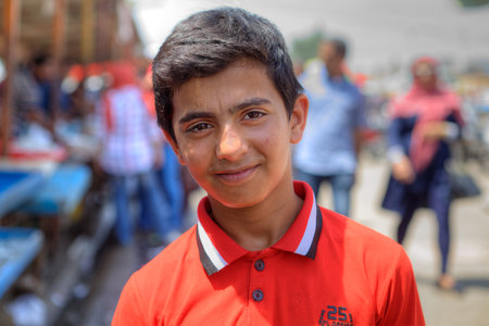 Bandar Abbas, Hormozgan Province, Iran - 16 april, 2017: One unknown Persian youth, about 14 years old, in an orange shirt, a close-up portrait against a city street background.のeditorial素材