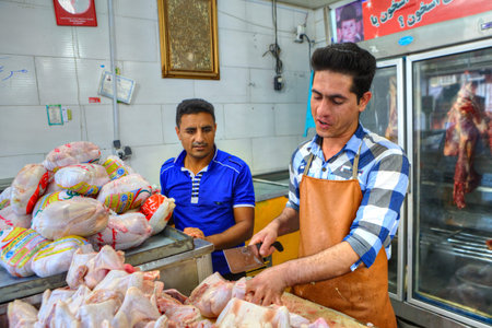 Bandar Abbas, Hormozgan Province, Iran - 16 april, 2017: Iranian butcher cuts up chicken carcasses at butcher shop.のeditorial素材
