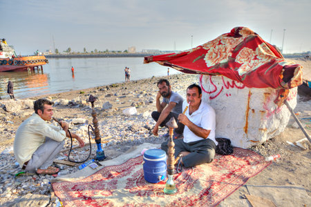 Bandar Abbas, Hormozgan Province, Iran - 16 april, 2017: Three men rest on the beach, two of them...