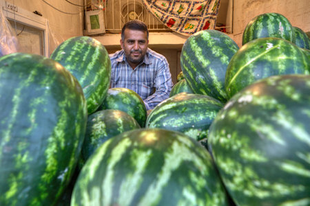 Bandar Abbas, Hormozgan Province, Iran - 16 april, 2017: Portrait of a seller in a huge pile of large watermelons.のeditorial素材