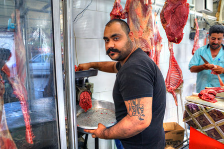Bandar Abbas, Hormozgan Province, Iran - 16 april, 2017: The butcher passes meat through a meat grinder, producing minced meat in a butcher's shop.のeditorial素材