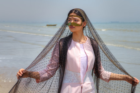 Bandari woman wears a traditional mask, beach of Persian Gulf, Hormozgan province, southern Iran.の写真素材