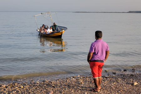 Bandar Abbas, Hormozgan Province, Iran - 16 april, 2017: One man looks like a boat with an Iranian family aboard, mooring to the shore.のeditorial素材